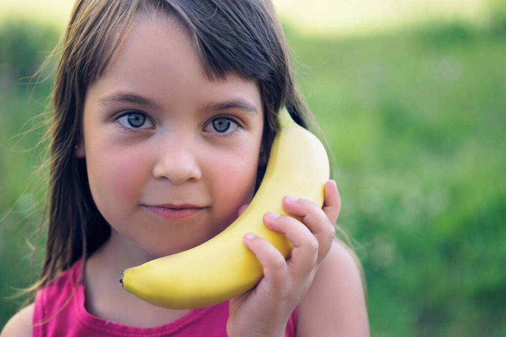 Kind speelt dat ze telefoneert met banaan