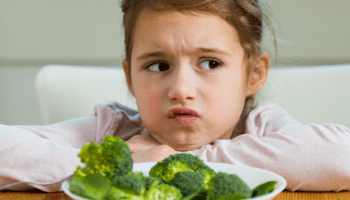 Kind trekt boos gezicht naar bord met groenten